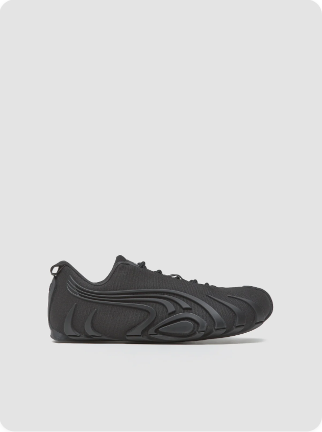Puma Mostro Triple Black - side profile showing full sculptural silhouette with flowing ridge texture, integrated lacing and black rubber outsole
